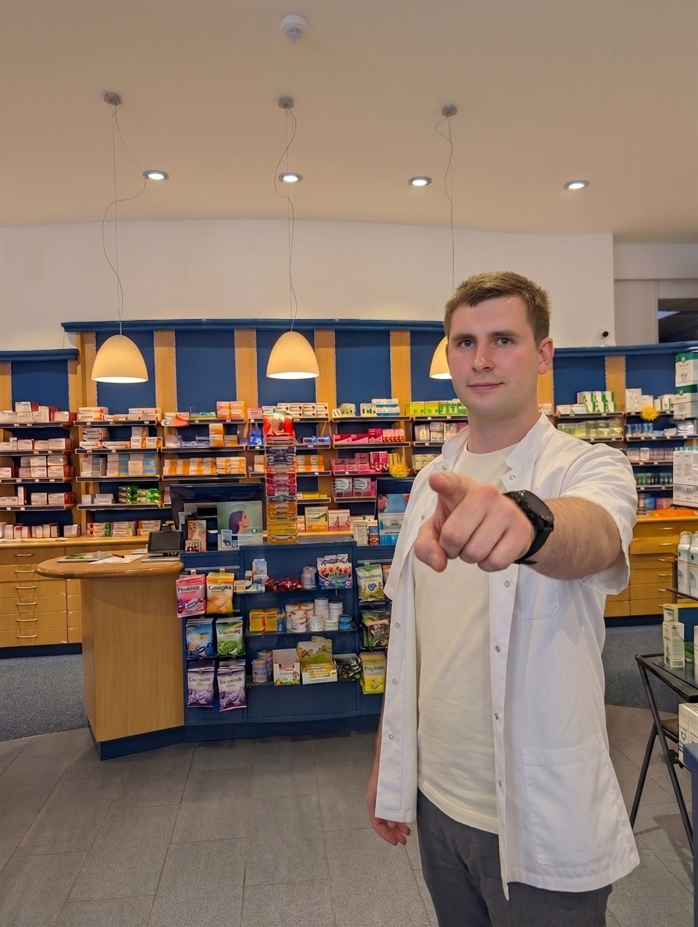 Apotheker der Stadt-Apotheke Meiningen zeigt einladend in die Kamera